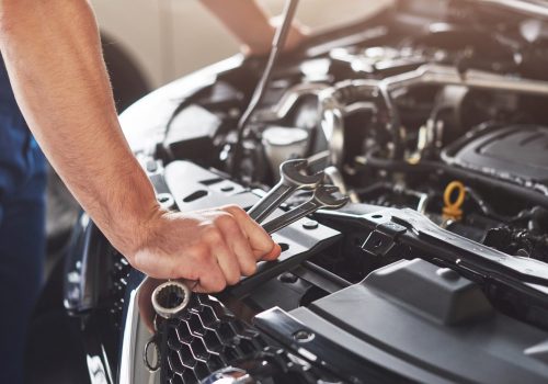 Picture showing muscular car service worker repairing vehicle.